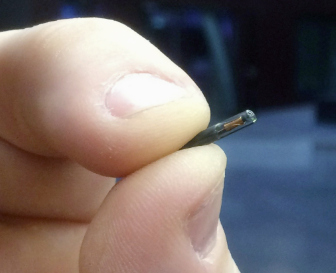 Close-up of a human hand with a visible subdermal NFC microchip implant under the skin showing the bioglass encapsulation